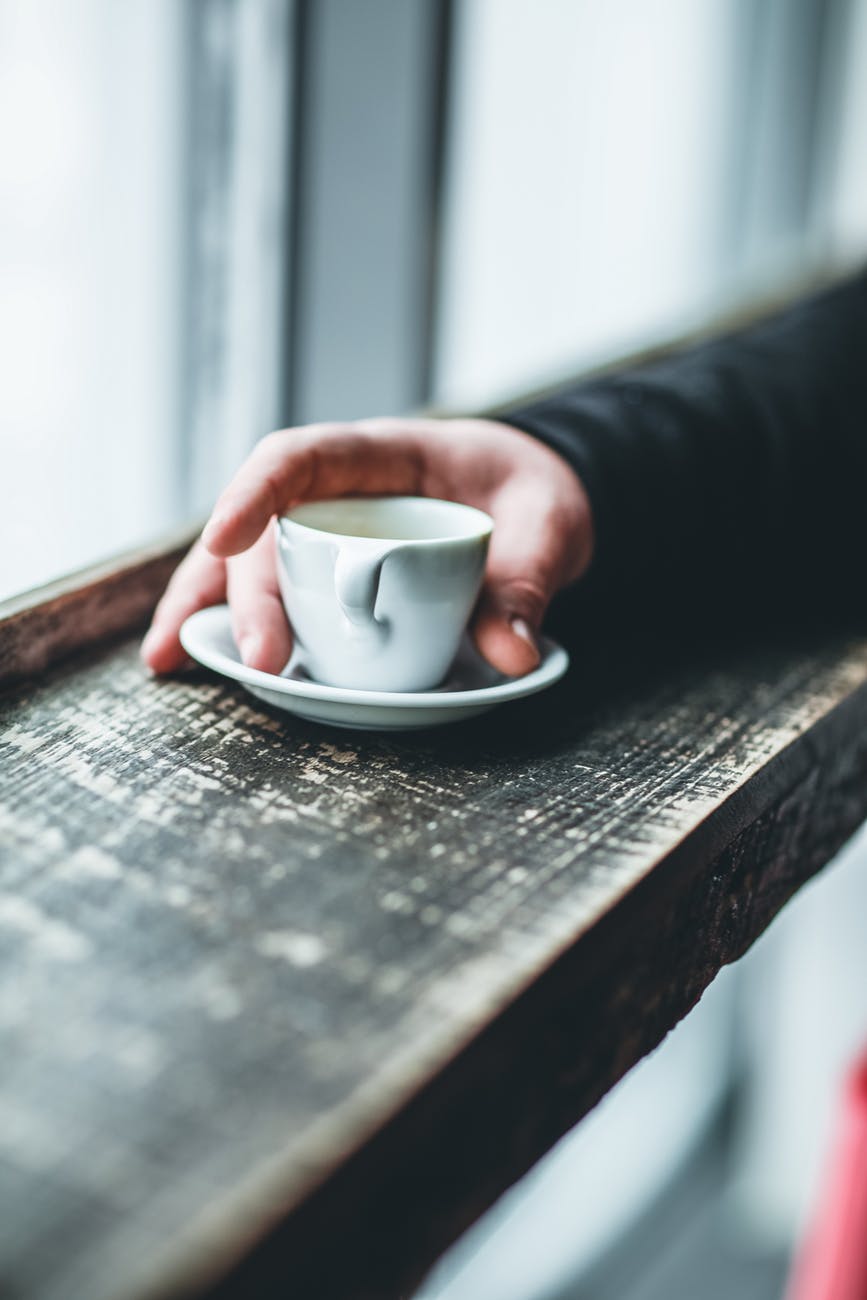 person holding white teacup